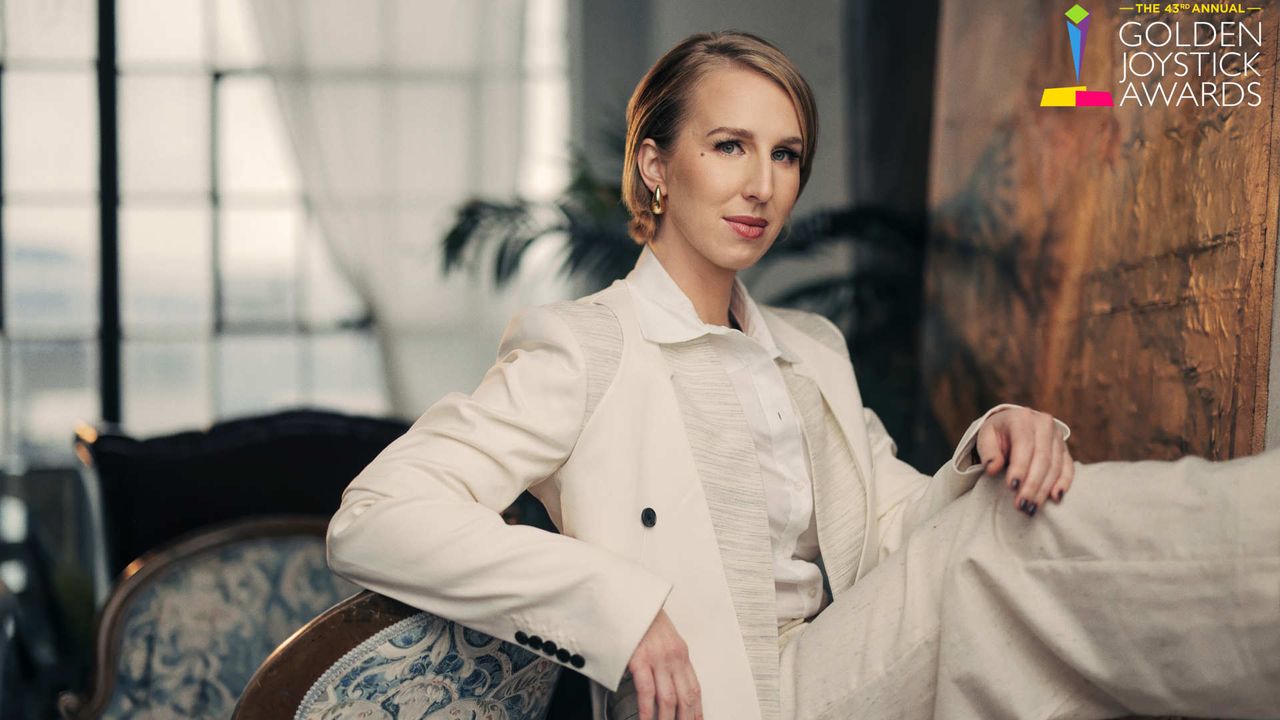 Golden Joystick Awards libera a lista de indicados a Jogo do Ano 1 Maggie Robertson sentada em poltrona moderna vestindo blazer branco elegante, com logo Golden Joystick Awards ao fundo